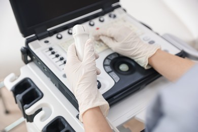 Photo of Sonographer with transducer and ultrasound machine in clinic, closeup