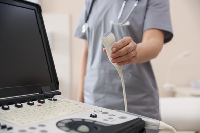 Photo of Sonographer with transducer and ultrasound machine in clinic, closeup
