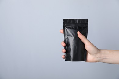 Photo of Woman with zipper stand-up pouch on grey background, closeup. Mockup for design