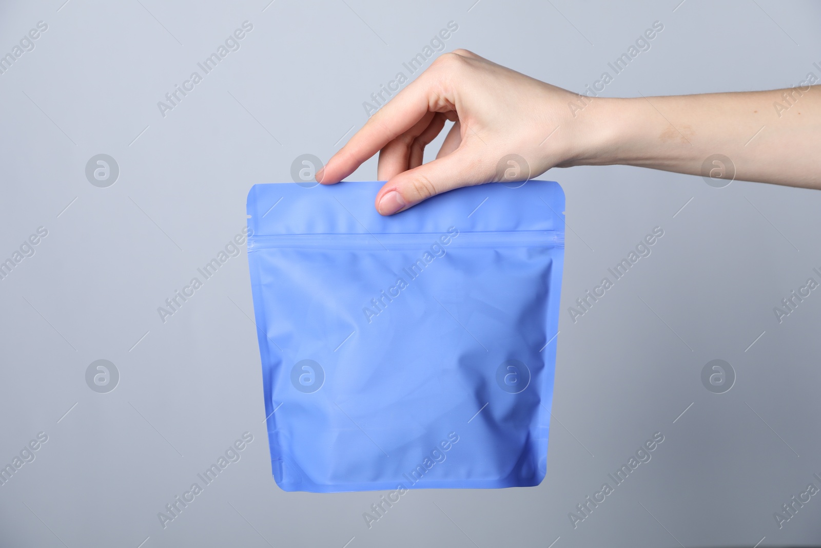 Woman with zipper stand-up pouch on grey background, closeup. Mockup for design Photo of Woman with zipper stand-up pouch on grey background, closeup. Mockup for design