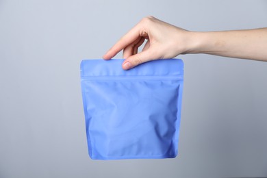 Photo of Woman with zipper stand-up pouch on grey background, closeup. Mockup for design