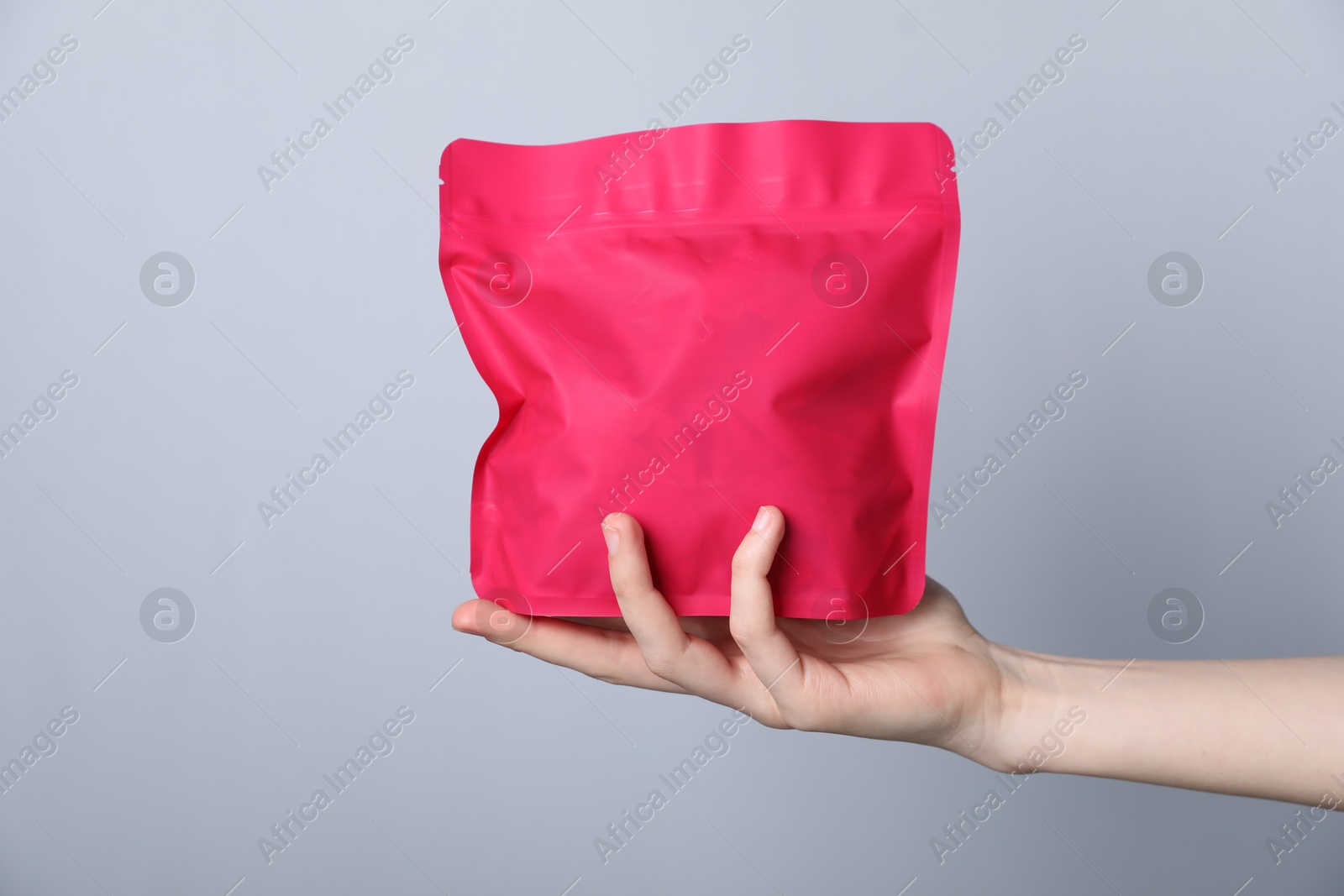 Woman with zipper stand-up pouch on grey background, closeup. Mockup for design Photo of Woman with zipper stand-up pouch on grey background, closeup. Mockup for design