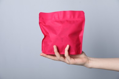 Photo of Woman with zipper stand-up pouch on grey background, closeup. Mockup for design