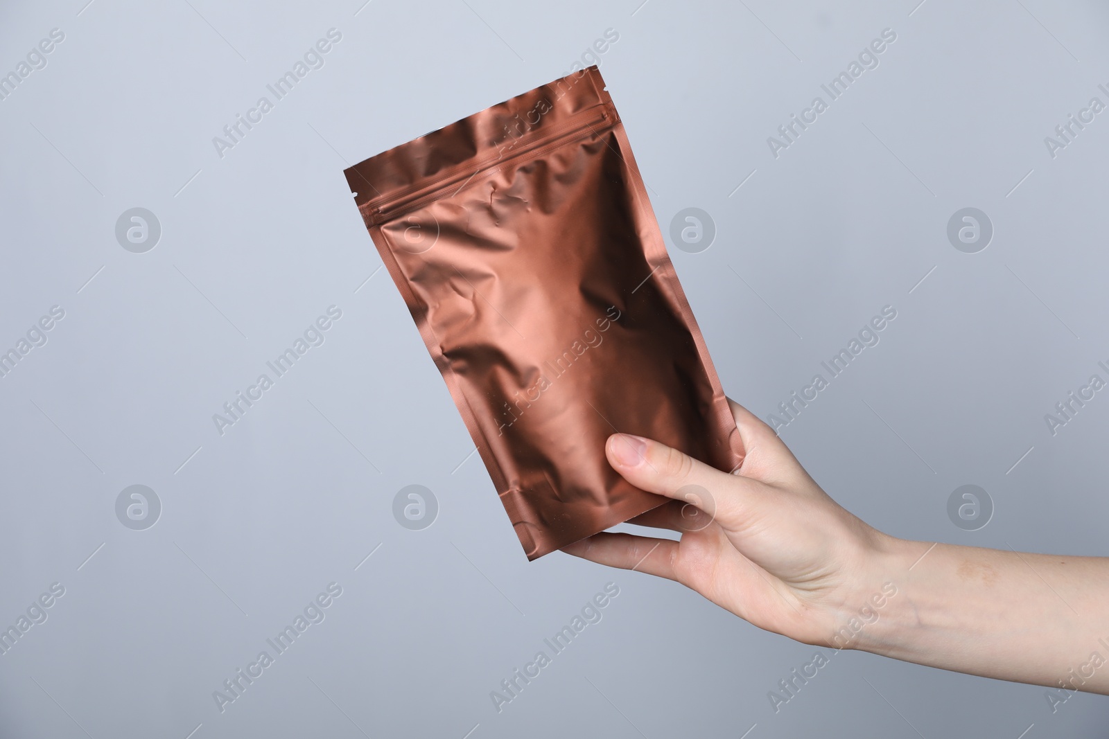 Woman with zipper stand-up pouch on grey background, closeup. Mockup for design Photo of Woman with zipper stand-up pouch on grey background, closeup. Mockup for design