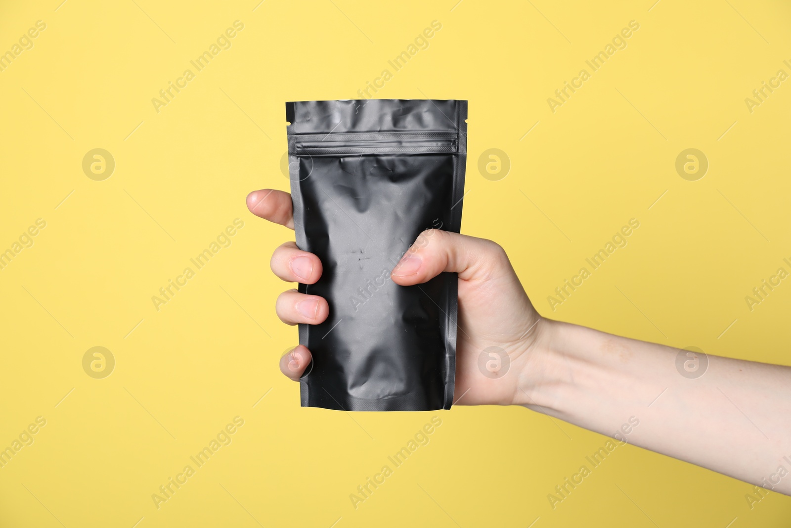 Woman with zipper stand-up pouch on yellow background, closeup. Mockup for design Photo of Woman with zipper stand-up pouch on yellow background, closeup. Mockup for design
