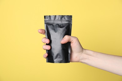 Photo of Woman with zipper stand-up pouch on yellow background, closeup. Mockup for design