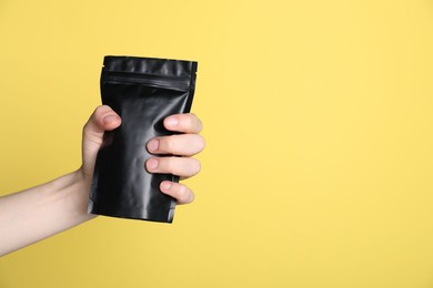 Photo of Woman with zipper stand-up pouch on yellow background, closeup. Mockup for design
