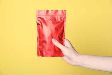 Photo of Woman with zipper stand-up pouch on yellow background, closeup. Mockup for design