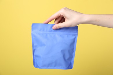 Photo of Woman with zipper stand-up pouch on yellow background, closeup. Mockup for design