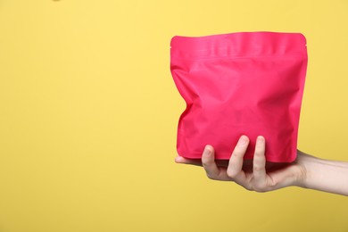 Photo of Woman with zipper stand-up pouch on yellow background, closeup. Mockup for design
