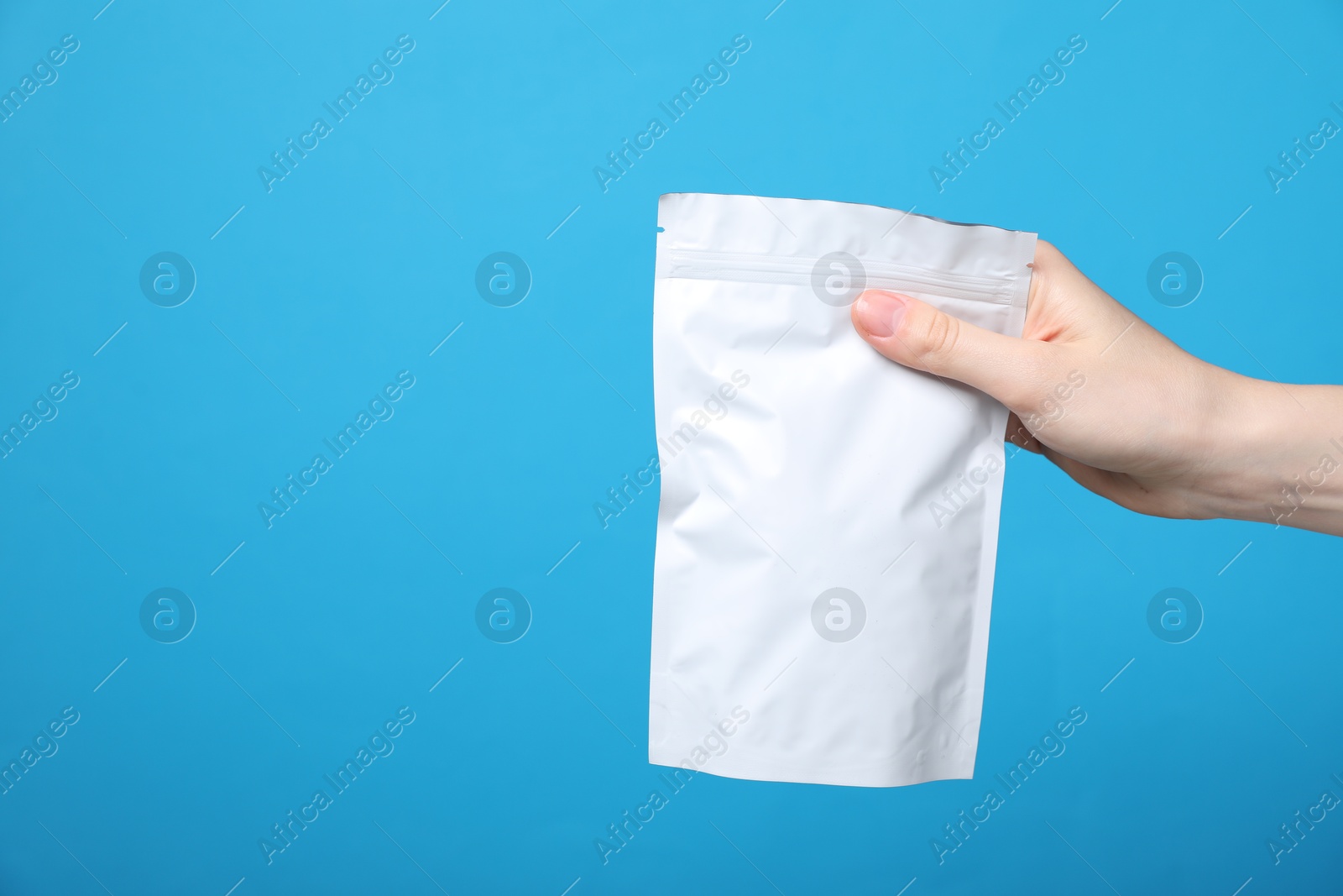 Woman with zipper stand-up pouch on light blue background, closeup. Mockup for design Photo of Woman with zipper stand-up pouch on light blue background, closeup. Mockup for design