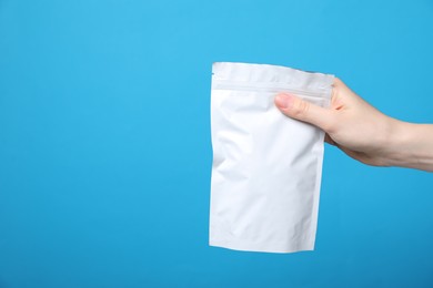 Photo of Woman with zipper stand-up pouch on light blue background, closeup. Mockup for design