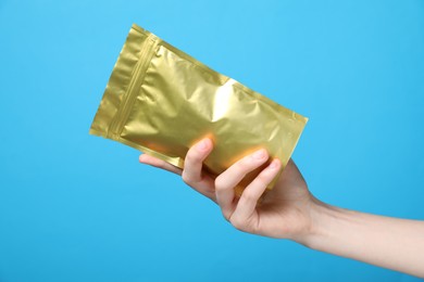Photo of Woman with zipper stand-up pouch on light blue background, closeup. Mockup for design