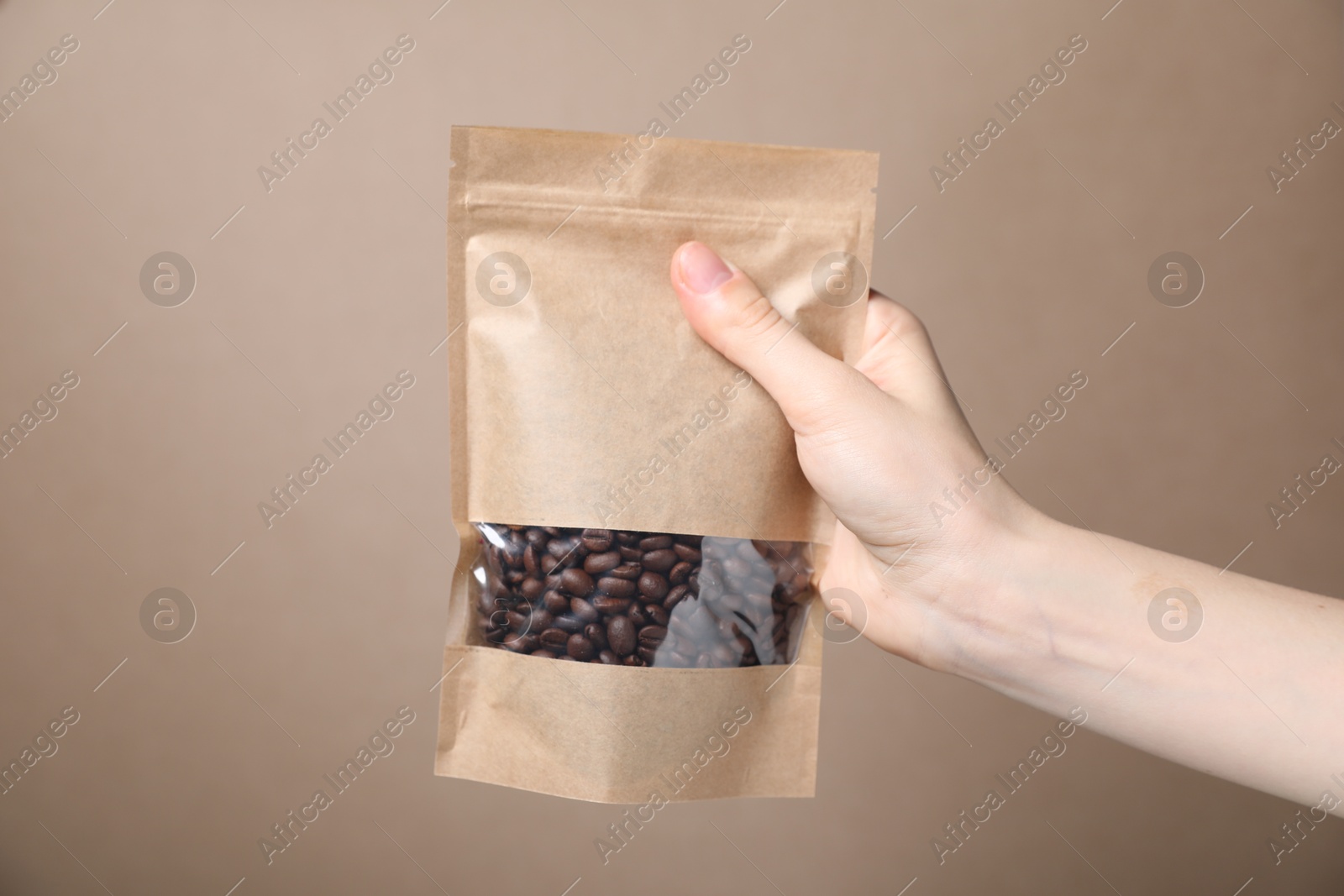 Woman holding zipper stand-up pouch with coffee beans on beige background, closeup. Mockup for design Photo of Woman holding zipper stand-up pouch with coffee beans on beige background, closeup. Mockup for design