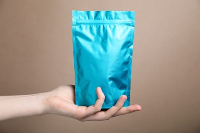 Photo of Woman with zipper stand-up pouch on beige background, closeup. Mockup for design