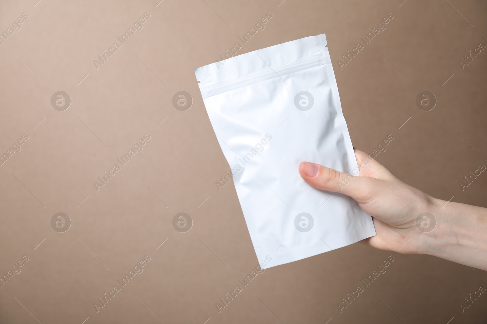 Woman with zipper stand-up pouch on beige background, closeup. Mockup for design Photo of Woman with zipper stand-up pouch on beige background, closeup. Mockup for design