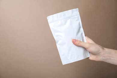 Photo of Woman with zipper stand-up pouch on beige background, closeup. Mockup for design
