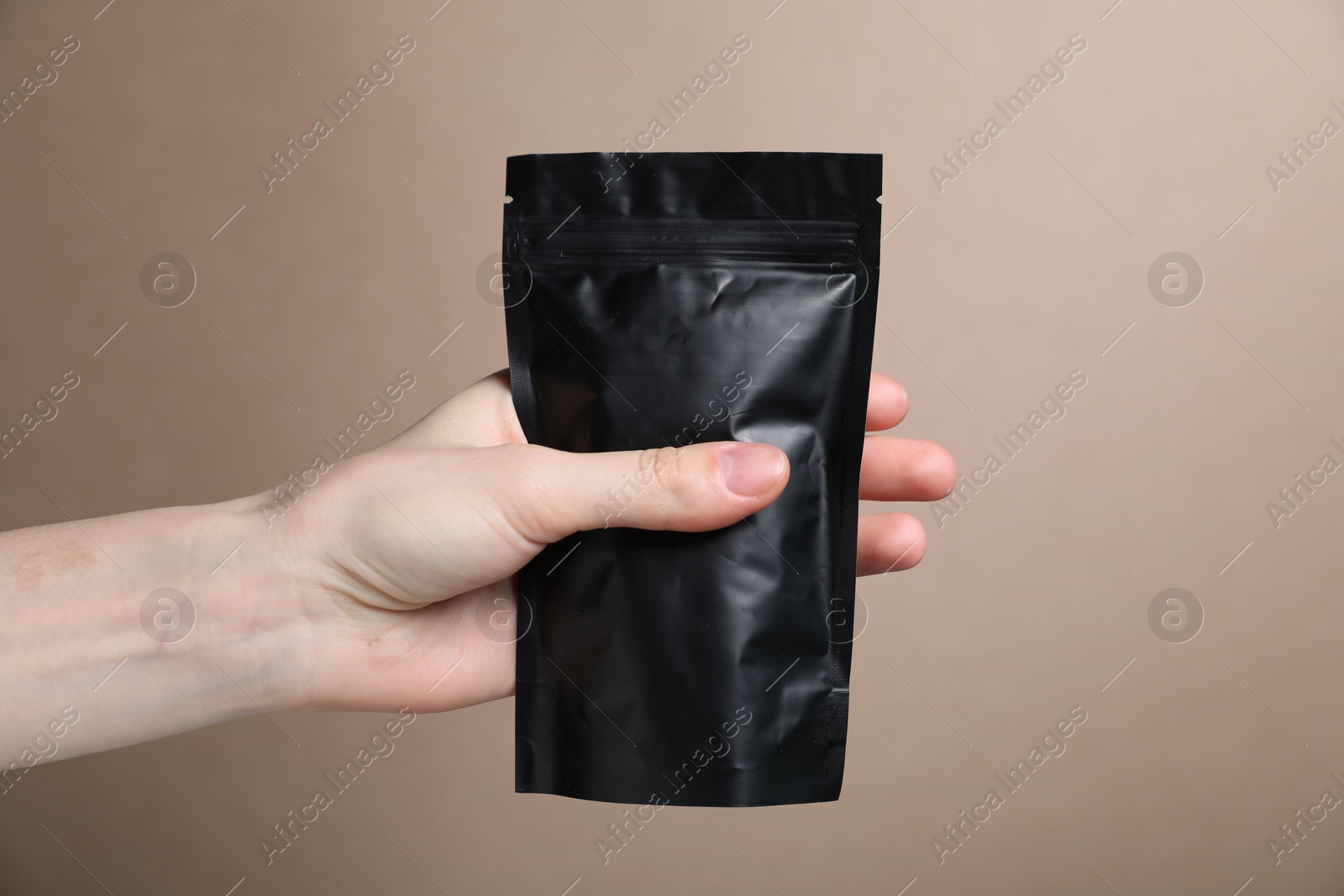 Woman with zipper stand-up pouch on beige background, closeup. Mockup for design Photo of Woman with zipper stand-up pouch on beige background, closeup. Mockup for design