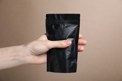 Photo of Woman with zipper stand-up pouch on beige background, closeup. Mockup for design