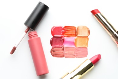 Photo of Colorful lip glosses and lipsticks on white background, flat lay
