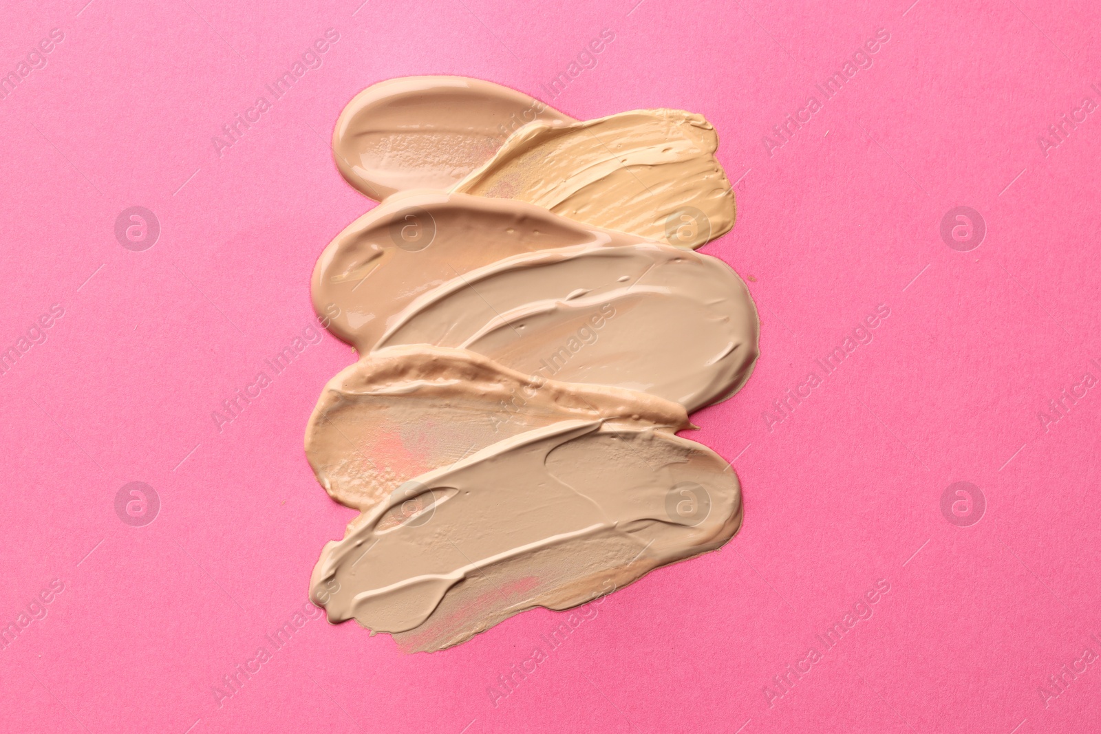 Colorful skin foundations on magenta background, above view Photo of Colorful skin foundations on magenta background, above view