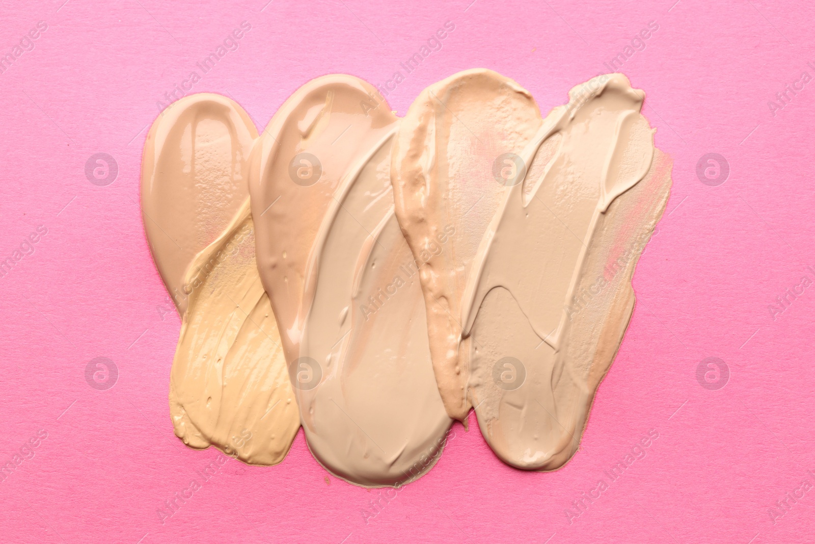Colorful skin foundations on magenta background, flat lay Photo of Colorful skin foundations on magenta background, flat lay