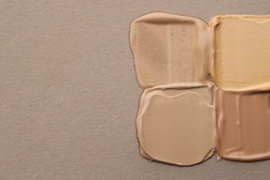 Photo of Colorful skin foundations on grey background, flat lay. Space for text