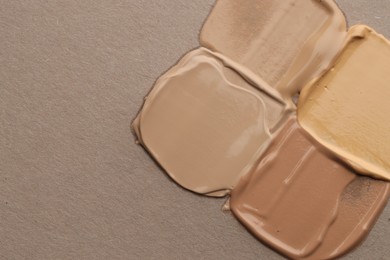 Photo of Colorful skin foundations on grey background, flat lay. Space for text