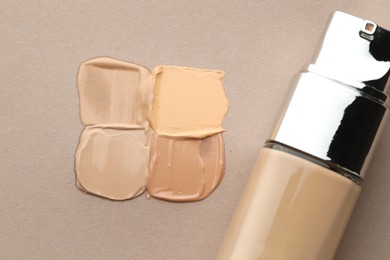 Photo of Colorful skin foundations and bottle on grey background, flat lay