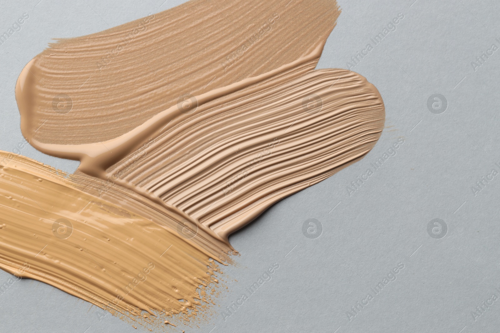 Photo of Colorful skin foundations on grey background, flat lay