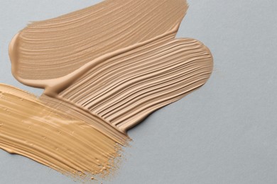 Photo of Colorful skin foundations on grey background, flat lay