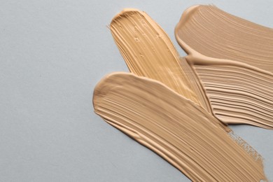 Photo of Colorful skin foundations on grey background, flat lay. Space for text