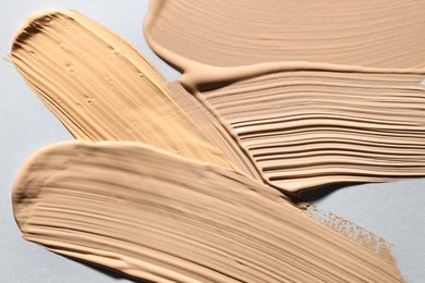 Photo of Colorful skin foundations on grey background, above view