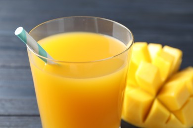 Photo of Tasty mango juice in glass and fresh fruit on table, closeup