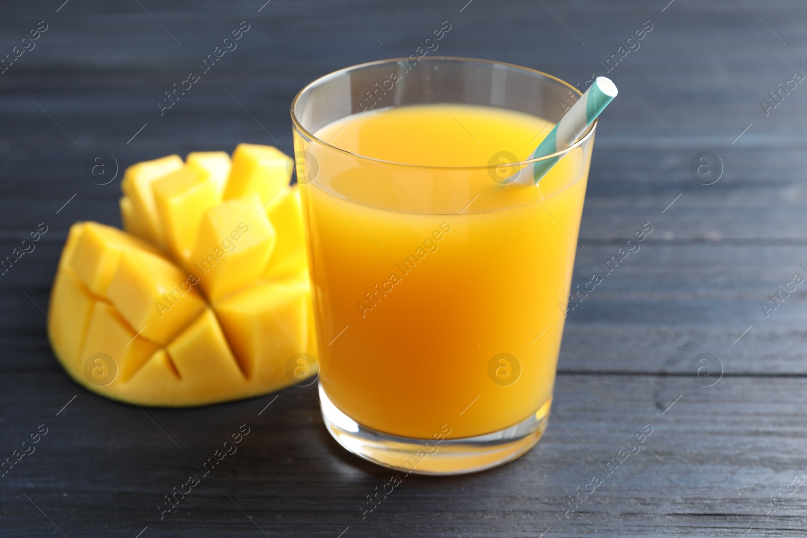 Tasty mango juice in glass and fresh fruit on wooden table, closeup Photo of Tasty mango juice in glass and fresh fruit on wooden table, closeup