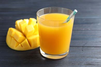 Photo of Tasty mango juice in glass and fresh fruit on wooden table, closeup