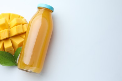 Photo of Tasty mango juice in glass bottle, fresh fruit and leaves on white background, flat lay. Space for text