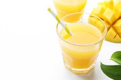 Photo of Tasty mango juice in glasses, fresh fruit and green leaves on white background, closeup. Space for text