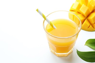 Photo of Tasty mango juice in glass, fresh fruit and green leaves on white background, closeup. Space for text