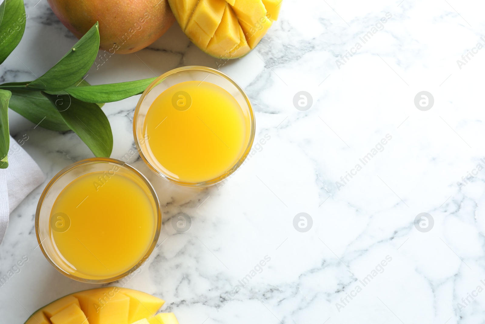 Tasty mango juice in glasses, fresh fruits and leaves on white marble table, flat lay. Space for text Photo of Tasty mango juice in glasses, fresh fruits and leaves on white marble table, flat lay. Space for text