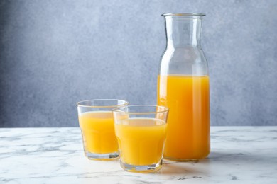 Photo of Tasty mango juice in glasses and carafe on white marble table
