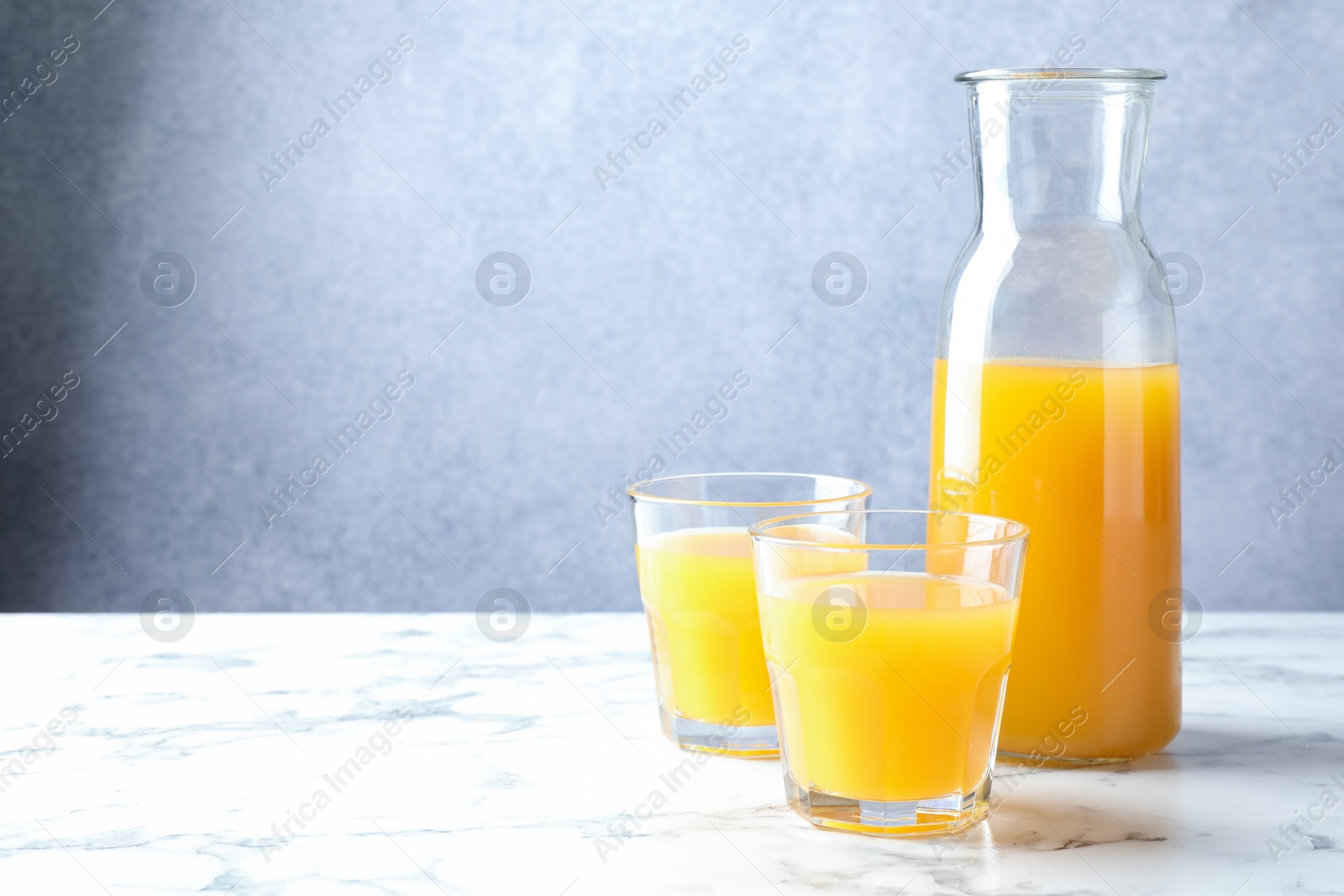 Tasty mango juice in glasses and carafe on white marble table, space for text Photo of Tasty mango juice in glasses and carafe on white marble table, space for text