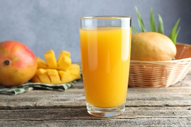 Photo of Tasty mango juice in glass and fresh fruits on wooden table