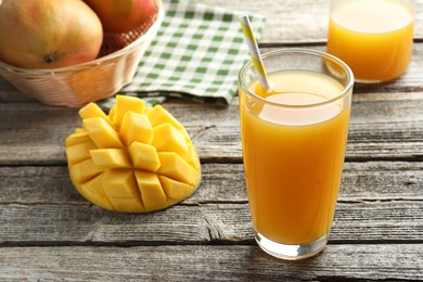 Photo of Tasty mango juice in glass and fresh fruits on wooden table, closeup