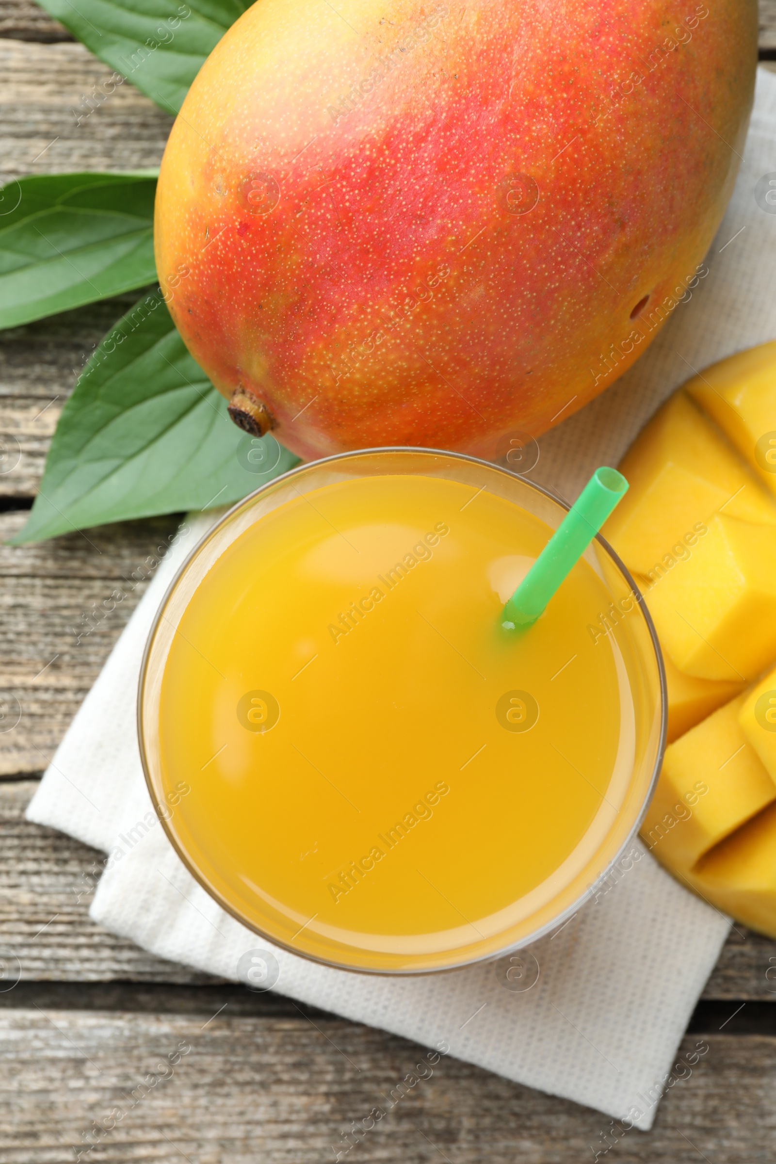 Tasty mango juice in glass, fresh fruits and green leaves on wooden table, flat lay Photo of Tasty mango juice in glass, fresh fruits and green leaves on wooden table, flat lay