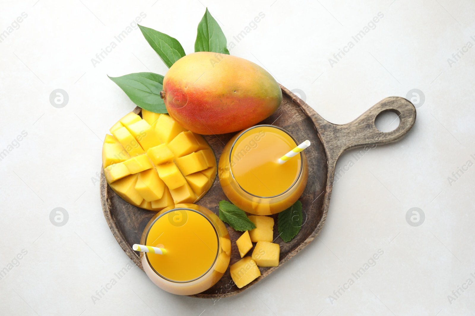 Tasty mango juice in glasses, fresh fruits, mint and green leaves on white table, top view Photo of Tasty mango juice in glasses, fresh fruits, mint and green leaves on white table, top view
