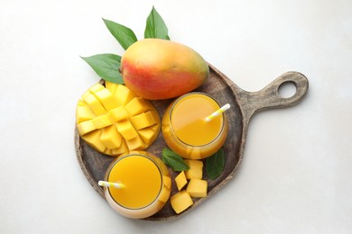 Photo of Tasty mango juice in glasses, fresh fruits, mint and green leaves on white table, top view