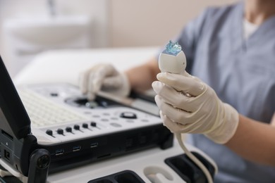 Photo of Sonographer holding ultrasound transducer with gel in clinic, closeup