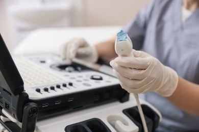 Photo of Sonographer holding ultrasound transducer with gel in clinic, closeup
