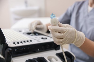 Photo of Sonographer holding ultrasound transducer with gel in clinic, closeup